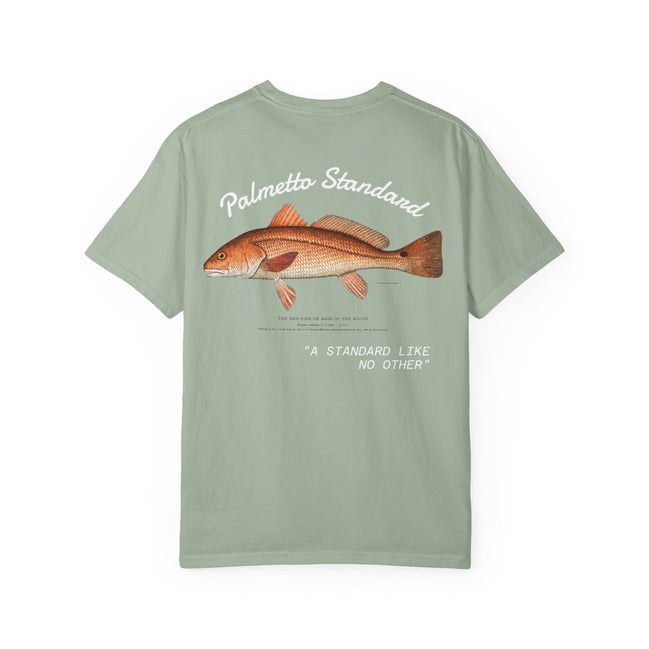 A sage green short-sleeve t-shirt shown from the back, featuring a graphic print of a redfish with the text 'Palmetto Standard' and 'A STANDARD LIKE NO OTHER' in white and orange.